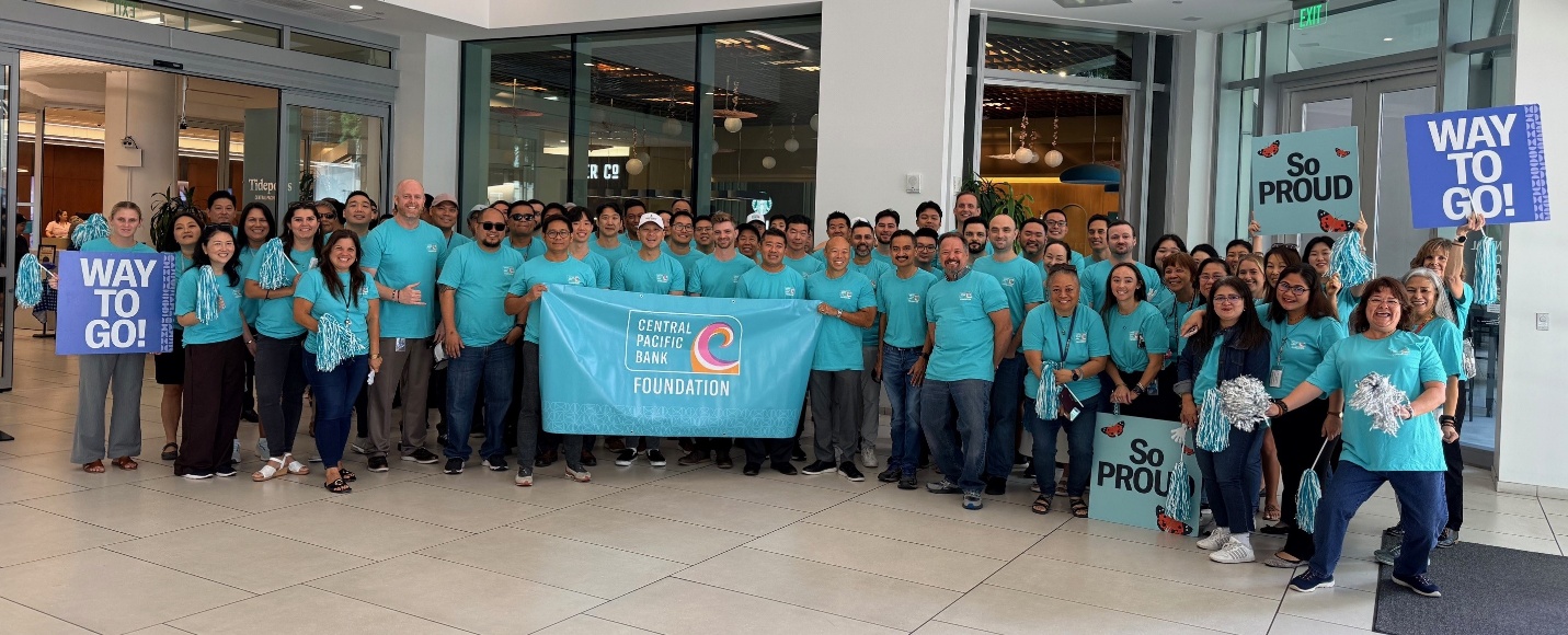 Men's March Against Violence partipants gather around the Central Pacific Bank Foundaton banner.
